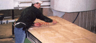 Una hoja ya optimizada (con las partes trazadas sobre la superficie de un panel) está ubicada sobre un router a CNC y es sopleteada para su limpieza antes de continuar el siguiente paso del proceso.